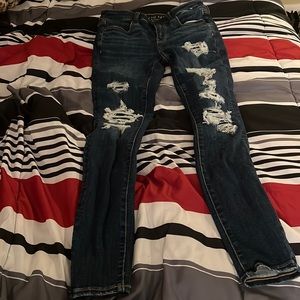 american egale dark navy blue jeans with patched holes .